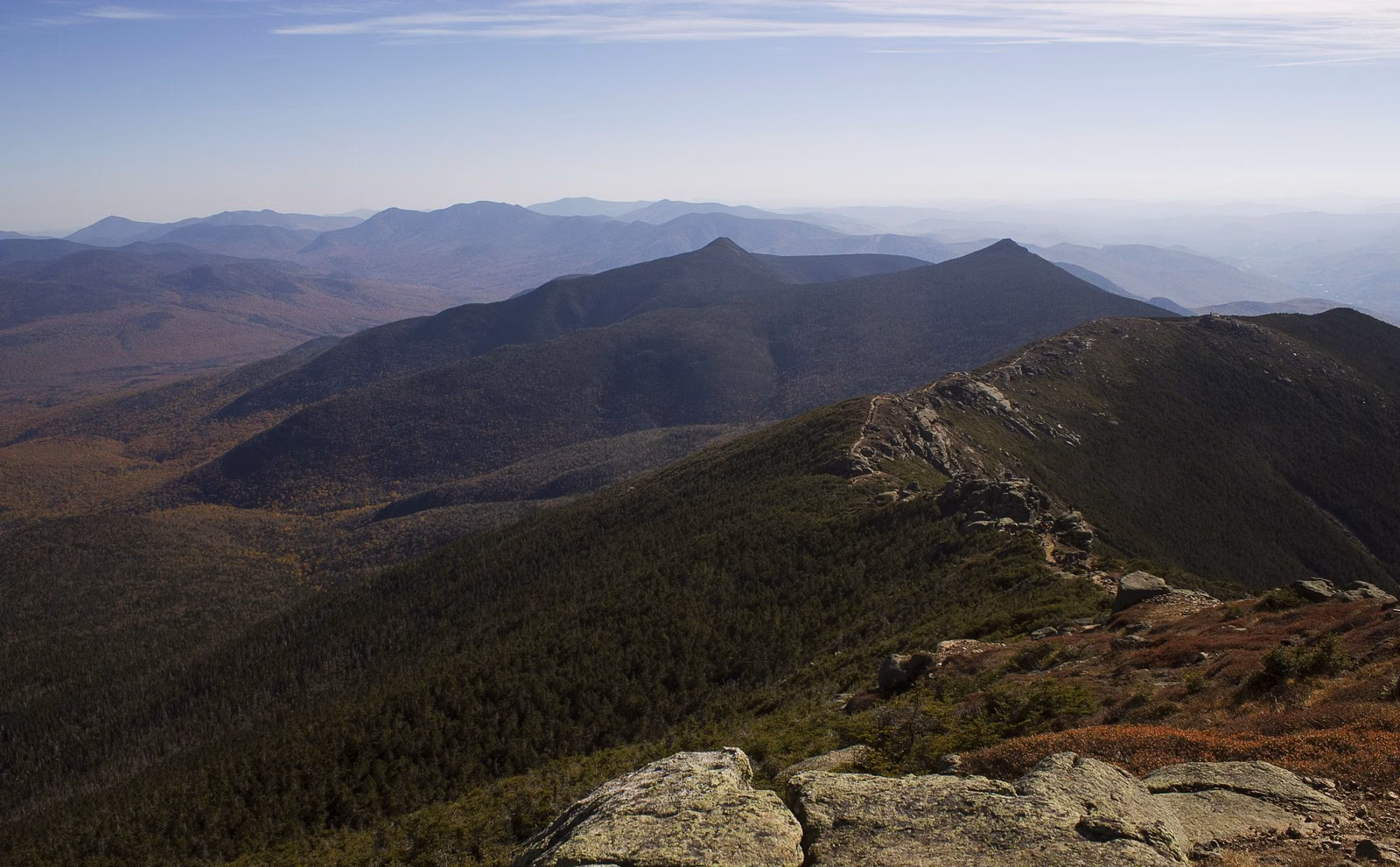 Open rocky ridgeline above forested mountains under a hazy sky in Franconia Notch State Park